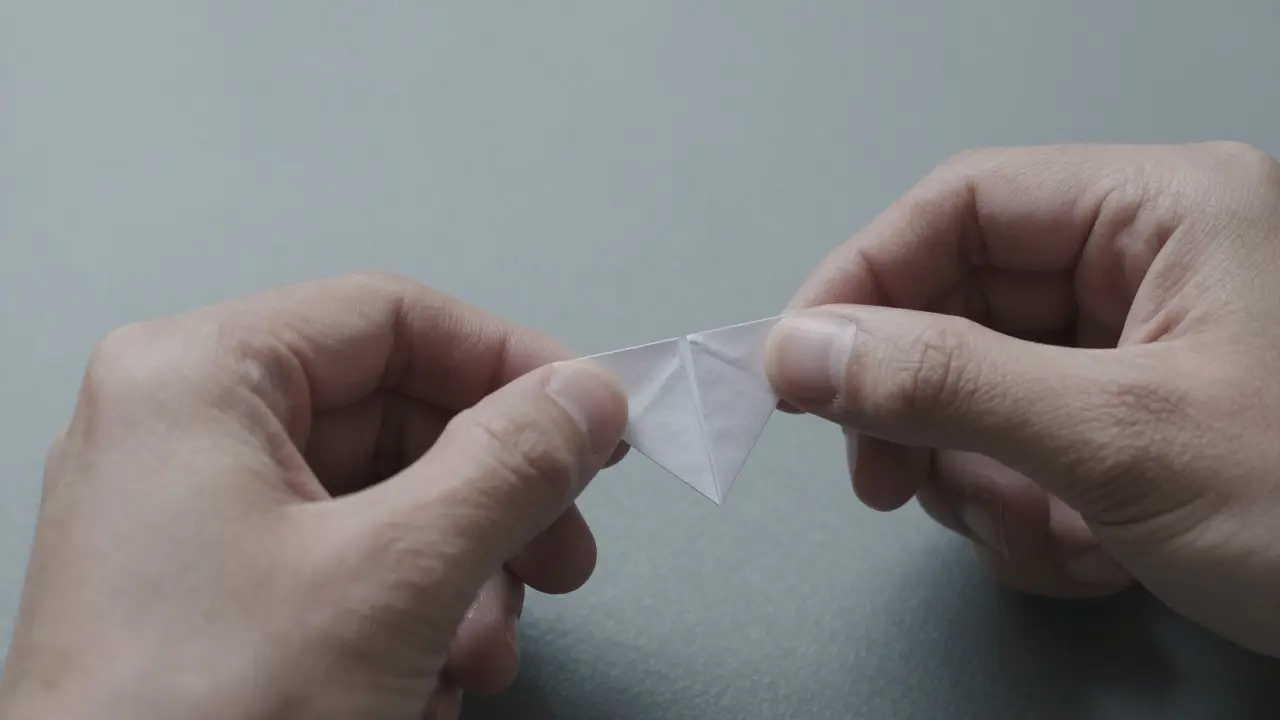Hands struggling to hold a minuscule origami token